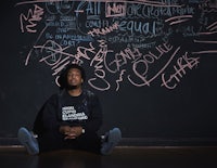 a man sitting in front of a blackboard with writing on it