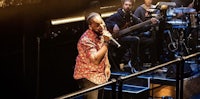 a man singing on stage in front of a group of musicians