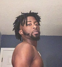 a black man with dreadlocks standing in a bathroom